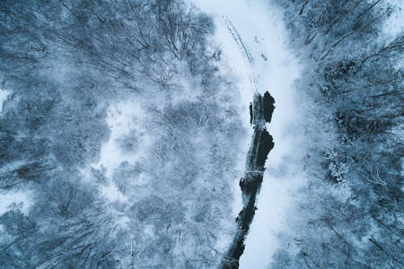 Winding river in the forest with snow and ice. Aerial photography from a drone.の写真素材