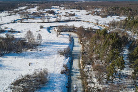 Beautiful Sunny landscape with forest, snow and frozen river. Aerial photography from a drone.