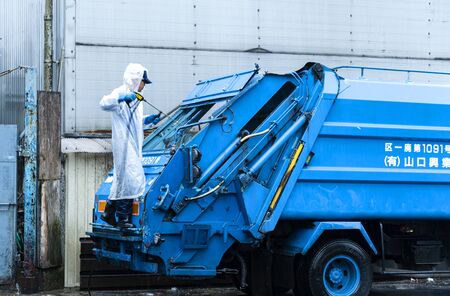 Tokyo, Japan - August 21, 2016: Worker is cleaning a trash truck during early morning hours