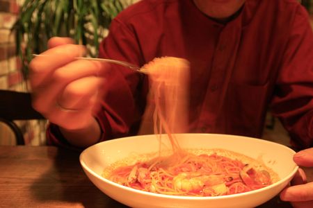 a japanese man eating spaghetti for his dinner. with a blur effect on his movementの写真素材