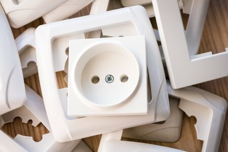 European power socket and the stack of socket frames on the light wooden table.