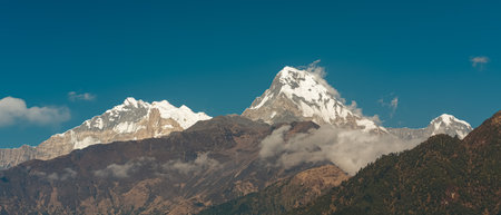 GHOREPANI, NEPAL - JANUARY 9, 2025: Stunning beauty of Annapurna range mountains, view from Ghorepani, warm light casts a serene glow over the ultra-wide landscape.の写真素材
