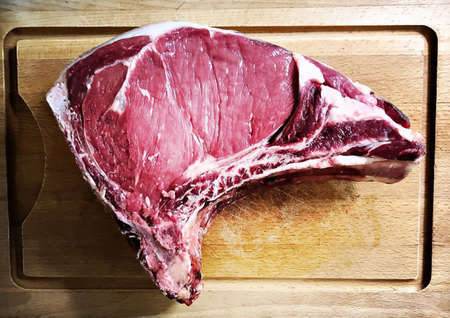 Uncooked big piece of red meat placed on the wooden table.