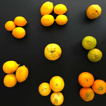 Yellowish and green grouped, arranged lemons, on the black background.