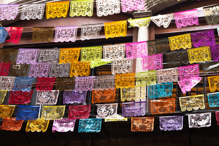 A colorful display of paper lanterns hangs from a building. The lanterns are of various colors and...