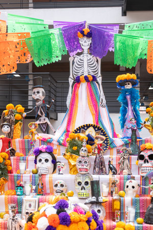 A table with many skeletons and flowers on it. The skeletons are dressed in colorful clothing. Day...