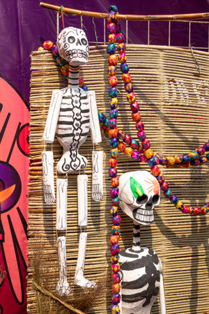 A skeleton is hanging from a bamboo pole with a colorful string. The skeleton is decorated with...
