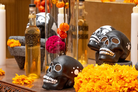 A table with skulls and flowers on it. The skulls are black and the flowers are orange. Day of the...