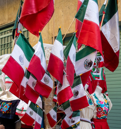 A display of Mexican flags hanging from a wall. The flags are red, white, and green. Decoration to...