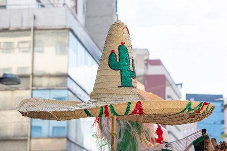 A hat with a green and red cactus on it. The hat is made of straw and is sitting on a pole....