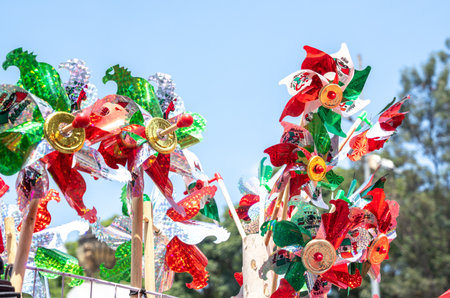 A bunch of windmills with red, white, and green decorations. The windmills are in a park and are...