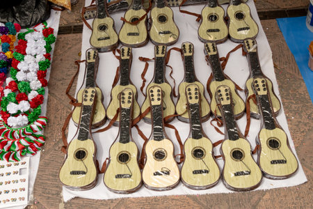 A row of guitars are displayed on a table. The guitars are all different sizes and colors. Historic...