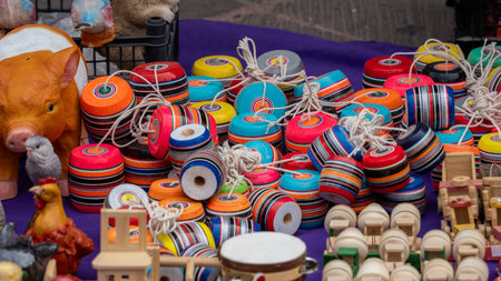 A pile of colorful kites and a pig toy are on a table. The kites are of various sizes and colors....