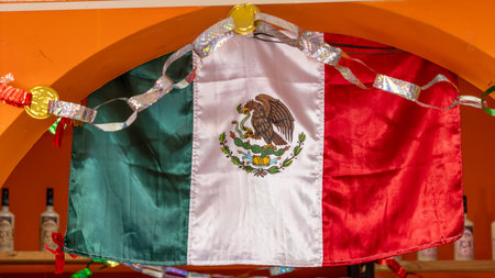 A Mexican flag is hanging from a wall. The flag is red, white, and green. Historic center of...