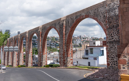 A stone arch bridge stretches across a street, connecting two sides of a city. Historic center of QuerÃ©taro, colonial architecture, decorations for the celebration of Mexico's Independence Day.の写真素材