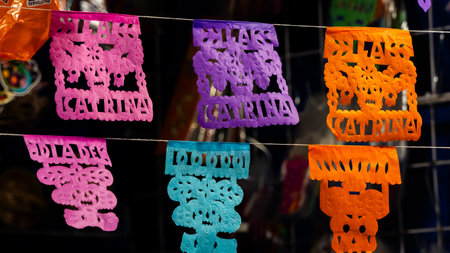 A colorful banner with the name "Catarina" written on it. The banner is hanging on a string. Mexican Day of the Dead tradition, offerings, food, colors, decorations, and papel picado, La Catrina.の写真素材