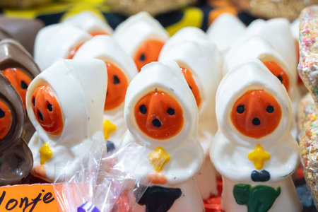 A bunch of Halloween-themed figures are on display in a store. They are all white and orange. Mexican Day of the Dead tradition, offerings, food, colors, decorations, and papel picado.の写真素材