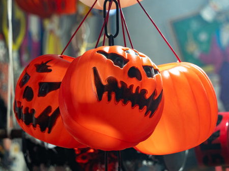 Three orange pumpkins with black faces hanging from a chain. The pumpkins have a creepy.の写真素材