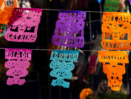 A collection of colorful paper flags with the name "Katrina" written on them are hanging on a line. Mexican Day of the Dead tradition, offerings, food, colors, decorations, and papel picado, La Catrina.の写真素材