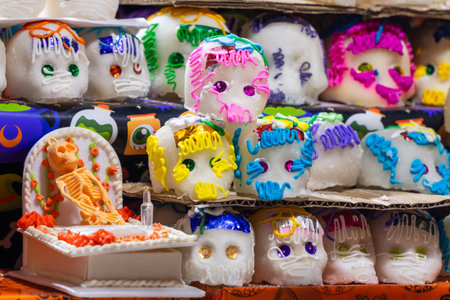 A table full of decorated sugar skulls. The skulls are in various colors and sizes. Mexican Day of the Dead tradition, offerings, food, colors, decorations, and papel picado, La Catrina.の写真素材