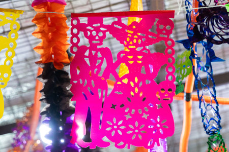 Pink paper with a skeleton and a woman on it. The skeleton is holding a guitar. Mexican Day of the Dead tradition, offerings, food, colors, decorations, and papel picado, La Catrina.の写真素材