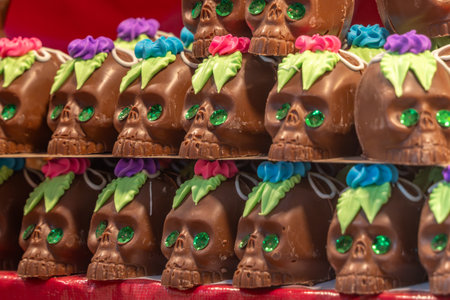 A row of chocolate skulls with green leaves on top. The skulls are decorated with green leaves. Mexican Day of the Dead tradition, offerings, food, colors, decorations, and papel picado, La Catrina.の写真素材