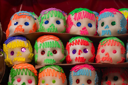 A display of colorful sugar skulls with various shades of green, red, and blue icing. Mexican Day of the Dead tradition, offerings, food, colors, decorations, and papel picado, La Catrina.の写真素材