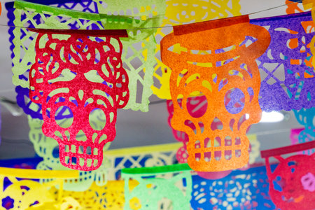 The colorful paper skulls hanging from the ceiling create a festive and lively atmosphere. Mexican Day of the Dead tradition, offerings, food, colors, decorations, and papel picado, La Catrina.の写真素材