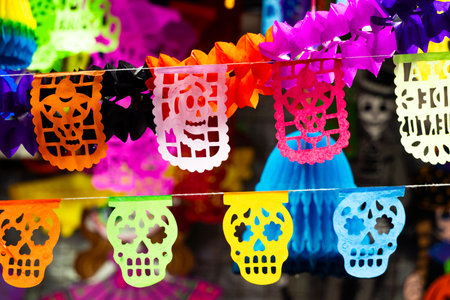 A colorful display of paper skulls and skeletons. The display is a mix of bright colors. Mexican Day of the Dead tradition, offerings, food, colors, decorations, and papel picado, La Catrina.の写真素材