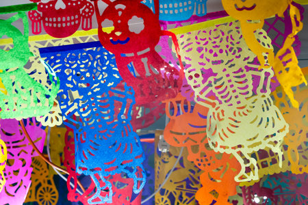 A colorful display of paper cutouts of skeletons and skulls. The display is made of paper. Mexican Day of the Dead tradition, offerings, food, colors, decorations, and papel picado, La Catrina.の写真素材