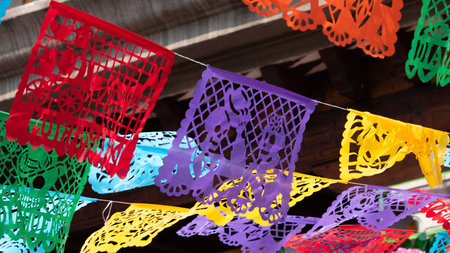 A colorful display of paper lanterns hang from the ceiling. The lanterns are of different colors. Mexican Day of the Dead tradition, offerings, food, colors, decorations, and papel picado.の写真素材