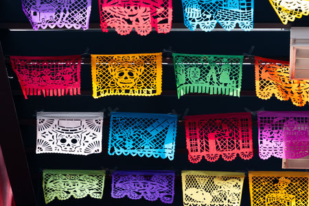 A colorful display of paper lanterns with skulls and other designs. Scene is festive and celebratory. Mexican Day of the Dead tradition, offerings, food, colors, decorations, and papel picado, La Catrina.の写真素材