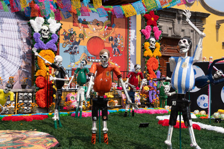 A lively scene of a group of skeletons dressed in costumes, standing in a field with a colorful back. Mexican Day of the Dead tradition, offerings, food, colors, decorations, and papel picado, La Catrina.の写真素材
