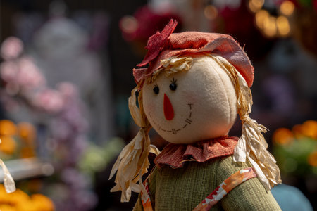 A scarecrow with a green dress and orange hat stands in front of a bunch of flowers. Mexican Day of the Dead tradition, offerings, food, colors, decorations, and papel picado.の写真素材