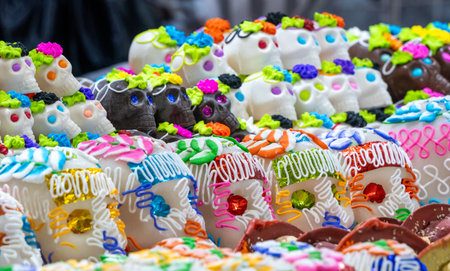 A colorful assortment of sugar skulls with different designs and colors. The image conveys a festive. Mexican Day of the Dead tradition, offerings, food, colors, decorations, and papel picado, La Catrina.の写真素材