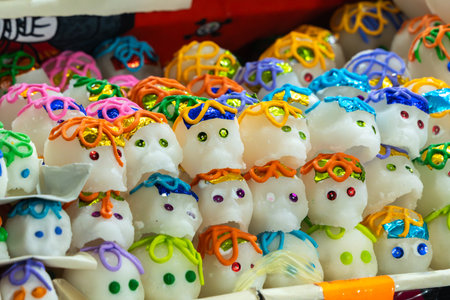 A box filled with a diverse collection of sugar skulls, each with its own unique face and color. Mexican Day of the Dead tradition, offerings, food, colors, decorations, and papel picado, La Catrina.の写真素材