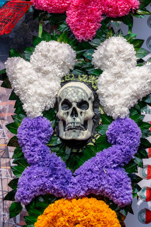 A flower arrangement with a skull and a heart. The skull is black and the heart is white. Mexican Day of the Dead tradition, offerings, food, colors, decorations, and papel picado, La Catrina.の写真素材