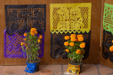 A wall adorned with various decorations, including potted plants and paper cutouts in the shape of s. Mexican Day of the Dead tradition, offerings, food, colors, decorations, and papel picado, La Catrina.の写真素材