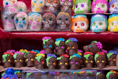 A display of colorful skulls and flowers. The skulls are decorated with frosting and candy. Mexican Day of the Dead tradition, offerings, food, colors, decorations, and papel picado, La Catrina.の写真素材