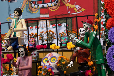 A group of skeletons are sitting on a balcony with a man in a green shirt and a woman in a white shirt. Mexican Day of the Dead tradition, offerings, food, colors, decorations, and papel picado, La Catrina.の写真素材