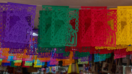 A colorful display of paper lanterns hang from the ceiling. The lanterns are in various colors. Mexican Day of the Dead tradition, offerings, food, colors, decorations, and papel picado.の写真素材