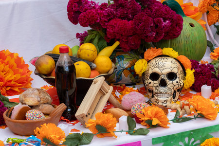 A table with a skull, fruit, and flowers. The skull is decorated with flowers. Mexican Day of the Dead tradition, offerings, food, colors, decorations, and papel picado, La Catrina.の写真素材