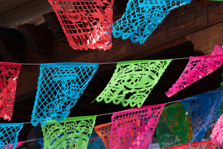 A colorful display of paper flags with a festive mood. The flags are in various colors and sizes. Mexican Day of the Dead tradition, offerings, food, colors, decorations, and papel picado, La Catrina.の写真素材