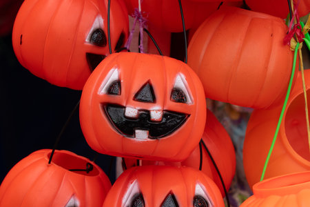 A bunch of orange pumpkins with black faces hanging from a string. The pumpkins are smiling. Mexican Day of the Dead tradition, offerings, food, colors, decorations, and papel picado.の写真素材