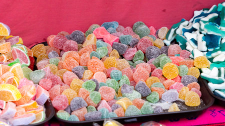 A tray of assorted colorful gummy bears and other candies. The tray is on a table. Mexican Day of the Dead tradition, offerings, food, colors, decorations, and papel picado.の写真素材