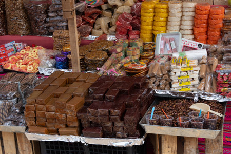 A table is filled with a variety of food items, including chocolate bars and other sweets. Mexican Day of the Dead tradition, offerings, food, colors, decorations, and papel picado.の写真素材