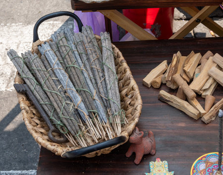 A basket filled with incense sticks is placed on a wooden table. Mexican Day of the Dead tradition, offerings, colors, decorations, and papel picado.の写真素材