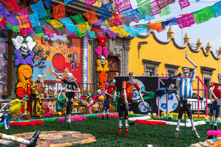 A colorful display of skeletons and other figures, including some dressed in soccer uniforms, is set. Mexican Day of the Dead tradition, offerings, food, colors, decorations, and papel picado, La Catrina.の写真素材
