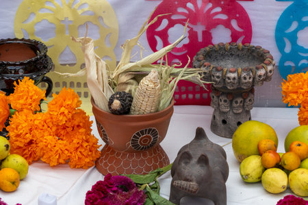 A table with a variety of fruits and vegetables, including oranges, apples, and corn. Mexican Day of the Dead tradition, offerings, food, colors, decorations, and papel picado, La Catrina.の写真素材