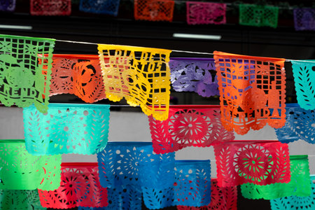 A vibrant collection of paper lanterns, each with the word "Happy" written on them, are hanging from. Mexican Day of the Dead tradition, offerings, food, colors, decorations, and papel picado, La Catrina.の写真素材